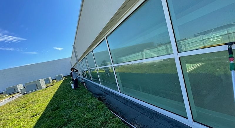 Industrial rooftop window cleaning in progress with a Tucker pole, effectively cleaning glass panels at height