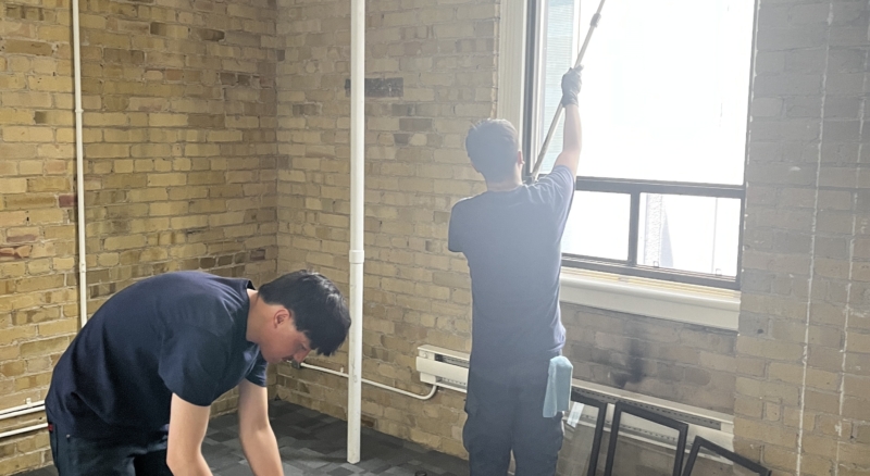 Tucker pole window cleaning in progress on a carpeted floor, with the worker cleaning hard-to-reach windows indoors.