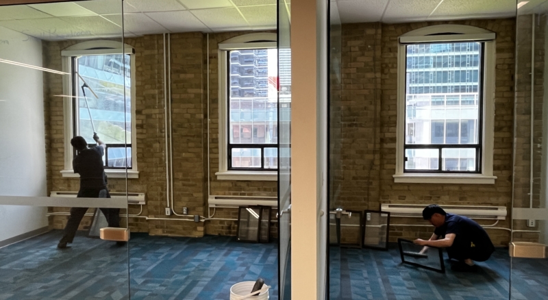 Worker performing interior window cleaning in a room with a carpeted floor, ensuring clean glass without damaging the carpet