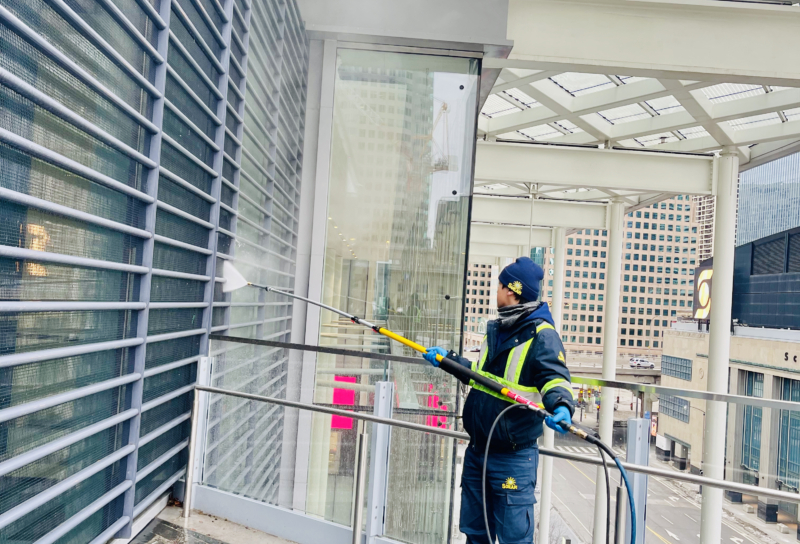 Pressure washing the exterior of a building, with water spray cleaning the facade to remove dirt and grime.