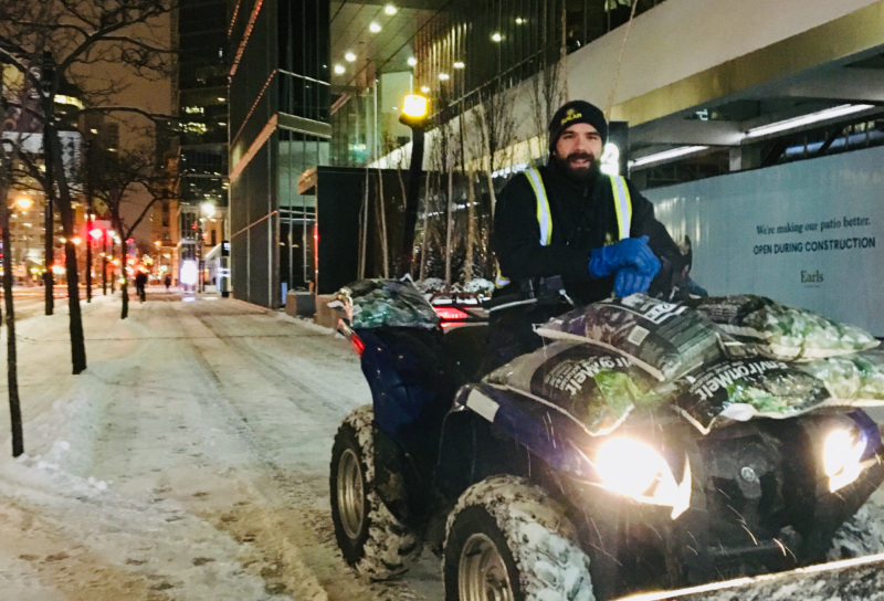 Snow removal using an ATV on the sidewalk in front of a commercial building, clearing snow for safe passage