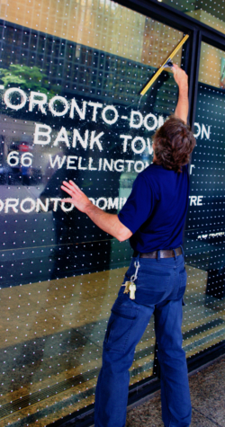 Day porter performing ground level window cleaning at TD Bank Tower in Toronto, maintaining the building's exterior glass