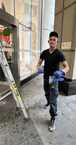 Employee preparing to use a ladder for window cleaning, setting up to reach high-rise glass windows