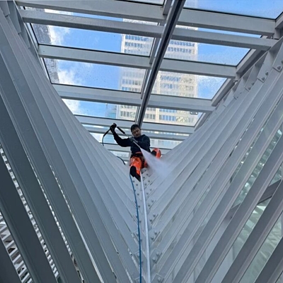 Pressure washing the ribs of Brookfield Place Galleria, Toronto, with a worker cleaning the architectural beams.