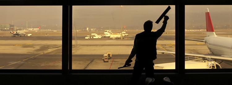 Worker cleaning airport window from inside