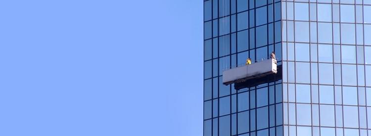 Workers on swing stage platform cleaning skyscraper